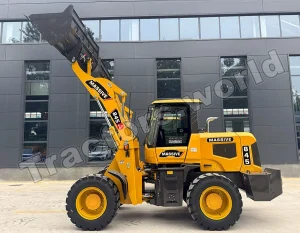 Yellow front-end loader with a raised bucket in front of a dark gray office building; labeled MASSIVE 845 on the arm (construction equipment).