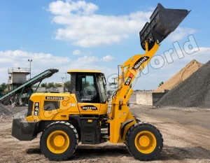 Yellow wheeled loader with raised bucket at a gravel quarry, yellow machinery and rock piles in background